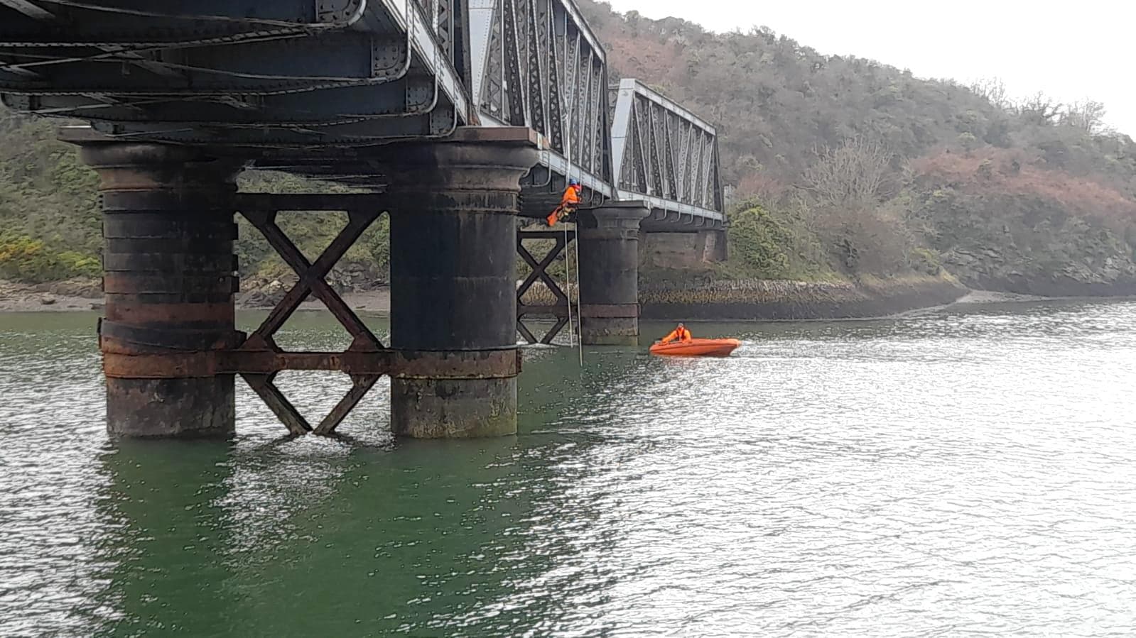 Little Petherick iron truss bridge on cast iron columns, with a rescue boat on the water